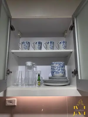 a cupboard with plates and cups and dishes at Cozy & Aesthetic 1 BR in BGC in Manila