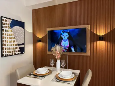 a dining room with a table with a tv on a wall at Cozy & Aesthetic 1 BR in BGC in Manila