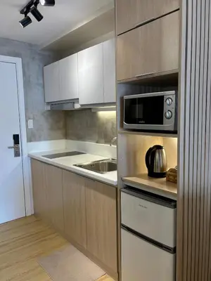 a kitchen with white cabinets and a microwave at 1LDK Air Studio in Makati City in Manila