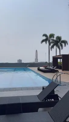 a large swimming pool with chairs and palm trees at LALAROOMS - with Manila Bay Sunset View in Manila