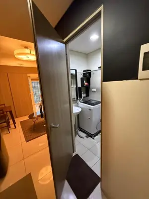 a bathroom with a door open to a kitchen at LALAROOMS - with Manila Bay Sunset View in Manila