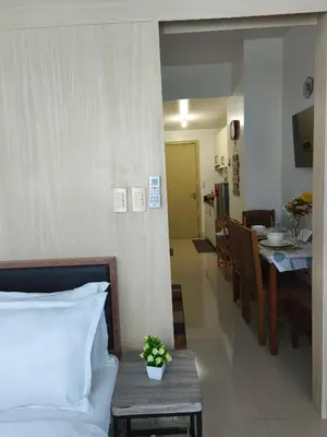 a bedroom with a bed and a table and a kitchen at City Staycation Condo-SM Jazz in Manila