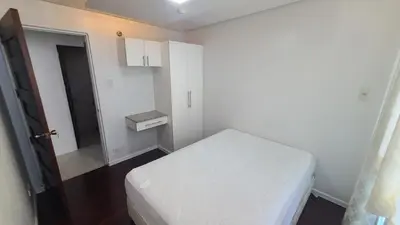 a small white room with a bed and a door at Central BGC - Spacious Modern 2 bedrooms 2 bathrooms with Balcony in Manila