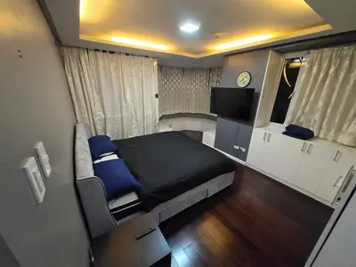 a bedroom with a bed and a tv in it at Central BGC - Spacious Modern 2 bedrooms 2 bathrooms with Balcony in Manila