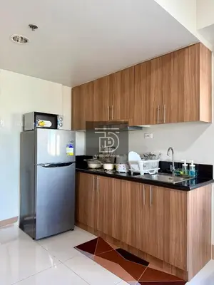 a kitchen with wooden cabinets and a stainless steel refrigerator at Shore 3 Tower 1 Condo staycation near MOA - DT in Manila