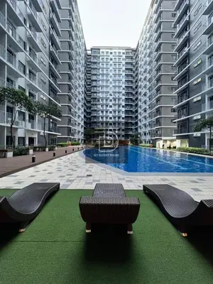 a large apartment complex with a swimming pool and two benches at Shore 3 Tower 1 Condo staycation near MOA - DT in Manila