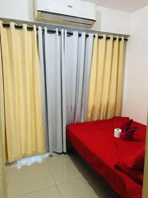 a bedroom with yellow and white curtains and a red bed at The Cozy Corner in Manila