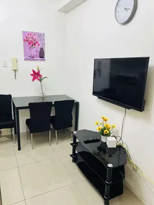 a living room with a table and a tv on the wall at The Cozy Corner in Manila