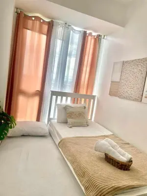 two twin beds in a room with a window at Aerith's Haven Azurecation in Manila