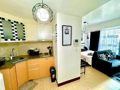 a kitchen and a living room with a couch and a table at Pasay Airport Condotel by ASD in Manila