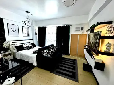 a bedroom with a bed and a couch and a table at Pasay Airport Condotel by ASD in Manila