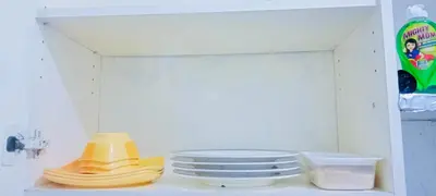 a shelf with plates and a stack of yellow dishes at Guest house avida condo in Manila