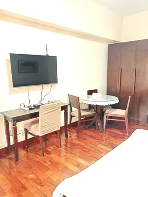 a dining room with a table and chairs and a tv at Mosaic Tower in Manila