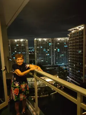 a woman standing on a balcony with a view of a city at Azure Staycation by Marco in Manila