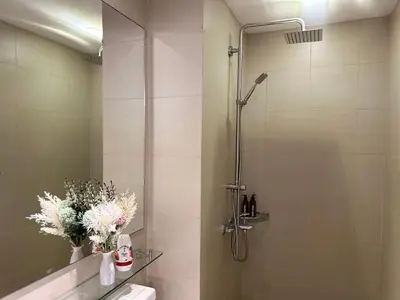 a bathroom with a shower with a toilet and flowers at Azure Staycation by Marco in Manila