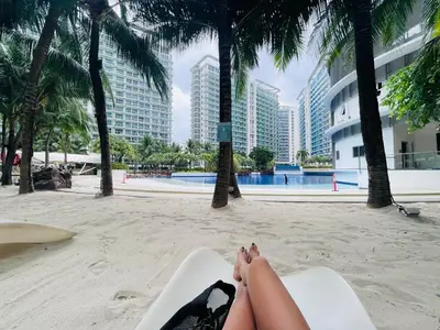 a woman laying on a surfboard on a beach at Azure Staycation by Marco in Manila