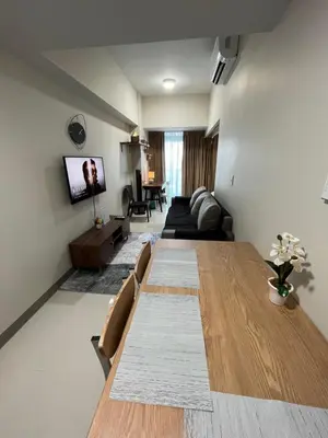 a living room with a long table and a couch at Uptown Parksuite 1 BR Tower 2 BGC Taguig in Manila