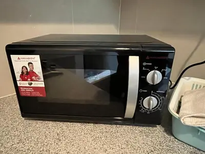 a black microwave with a magazine on top of it at Uptown Parksuite 1 BR Tower 2 BGC Taguig in Manila