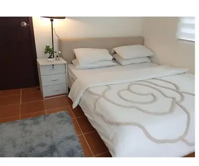 a bedroom with a bed and a nightstand with a white bedspread at 2BR PIONEER Woodland Boni,Mandaluyong connected to Boni MRT station in Manila