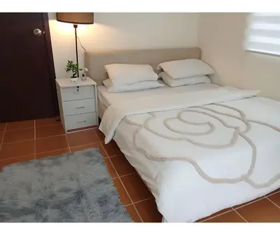a bedroom with two beds and a nightstand with a bedskirts at 2BR PIONEER Woodland Boni,Mandaluyong connected to Boni MRT station in Manila