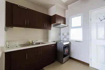 a kitchen with brown cabinets and a sink and a window at Millionaire Manila Bay Sunset Penthouse views in Manila