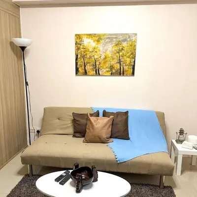 a living room with a couch and a painting on the wall at Crizzy's Hub Sariel at Shore Residences - 1BR with Netflix and Disney - Near MOA in Manila