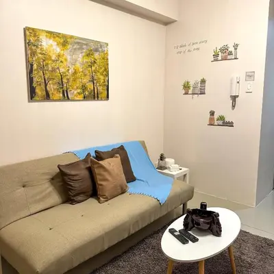 a living room with a couch and a painting on the wall at Crizzy's Hub Sariel at Shore Residences - 1BR with Netflix and Disney - Near MOA in Manila
