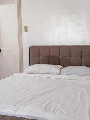 a large bed with white sheets and a brown headboard at 6-Bedroom Duplex with pool near NAIA in Manila