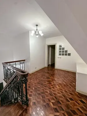 an empty living room with a staircase and wooden floor at 6-Bedroom Duplex with pool near NAIA in Manila