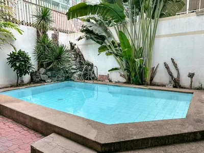 a swimming pool in a garden with plants at 6-Bedroom Duplex with pool near NAIA in Manila