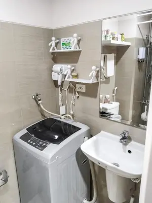 a bathroom with a sink and a washing machine at Crizzy's Hub Gabrielle at Shore Residences in Manila