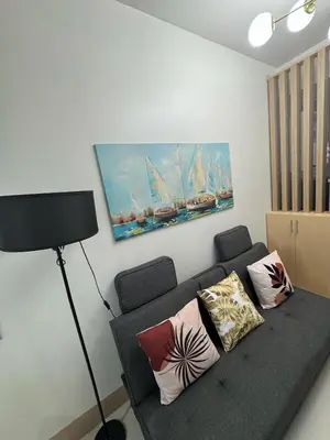 a living room with a couch with pillows and a painting at The Shore Residence in Manila