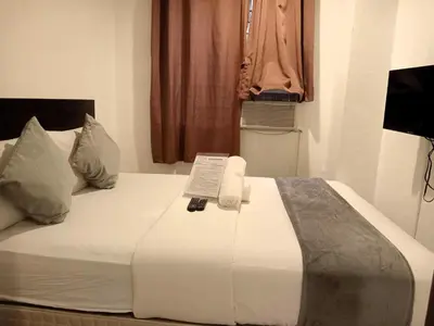 a large white bed with a remote control on it at Circuit Suites in Manila