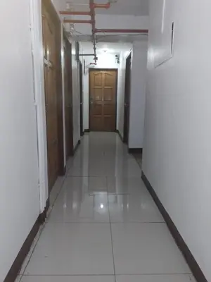 an empty hallway with doors and a tile floor at Circuit Suites in Manila