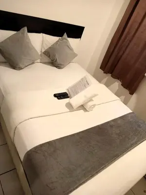 a bed with a remote control on top of it at Circuit Suites in Manila