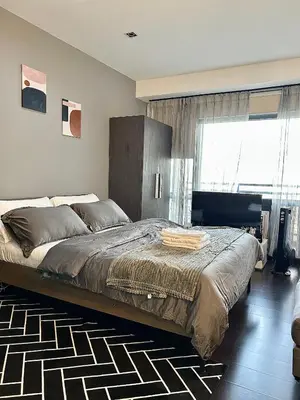 a bedroom with a large bed and a window at Sky-High Studio with Netflix, Sunset View, and Disney in Manila