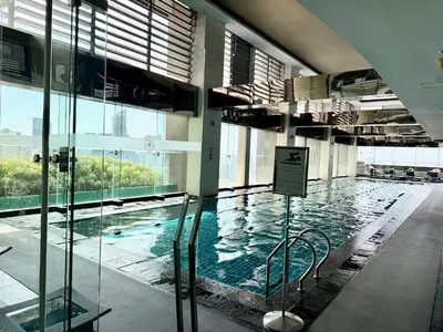 a large swimming pool in a building with glass walls at Sky-High Studio with Netflix, Sunset View, and Disney in Manila