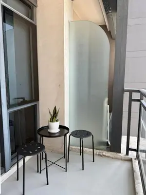 a table and two stools with a plant on a balcony at Sky-High Studio with Netflix, Sunset View, and Disney in Manila