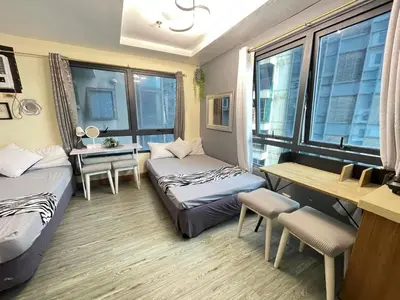 a room with two beds and a desk and windows at ADB Avenue Tower GOOD FOR 5 PAX in Manila