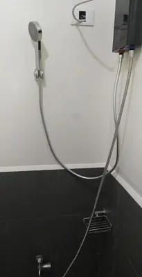 a shower with a hose attached to a wall at Deca Cubao Budget Condo by Ashti in Manila
