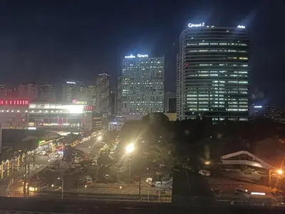 a city lit up at night with tall buildings at Deca Cubao Budget Condo by Ashti in Manila