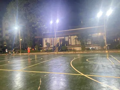 a person is playing basketball on a basketball court at night at East Raya Gardens Pasig near Ortigas BGC Eastwood in Manila