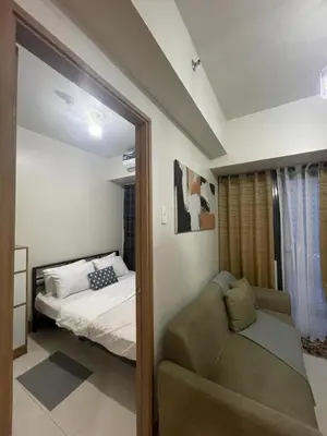 a bedroom with a bed and a couch and a mirror at Gen Travel Hub in Manila
