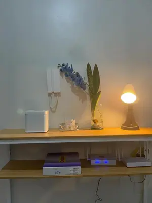 a desk with a lamp and a vase of flowers on it at Gen Travel Hub in Manila