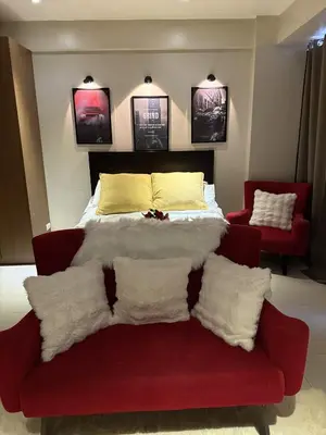 a bedroom with a bed and a couch with pillows at Bnb88C Condotel in Manila