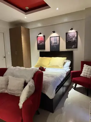 a bedroom with a bed and two red chairs at Bnb88C Condotel in Manila
