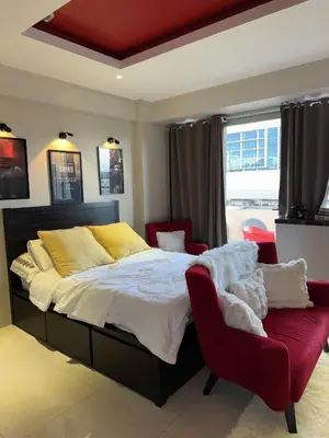 a bedroom with a large bed and a red chair at Bnb88C Condotel in Manila