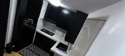 a small kitchen with black cabinets and a stove at DPMC Stay and Play Vacation Unit in Cainta