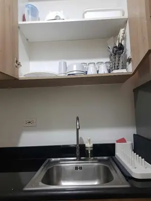 a kitchen sink with cups and dishes on a shelf at Shore2n3 Residences MOA Pasay City Near NAIA Airport in Manila