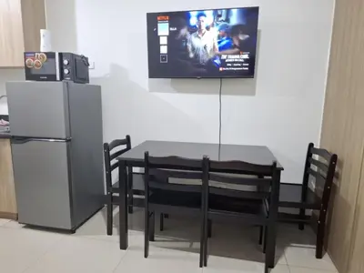a dining room table with a refrigerator and a television at Shore2n3 Residences MOA Pasay City Near NAIA Airport in Manila